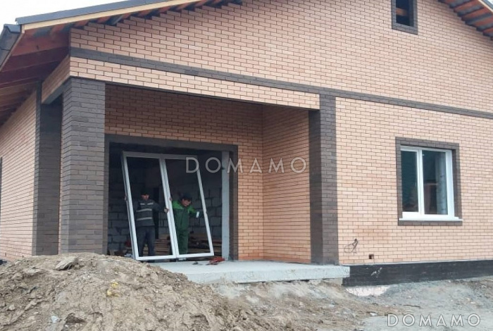 Проект одноэтажного дома из газобетона со стеклянным эркером в просторной гостиной и гаражом на два автомобиля с кирпичной облицовкой